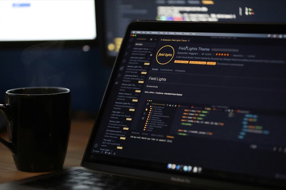 Code on a laptop screen next to a cup of coffee.