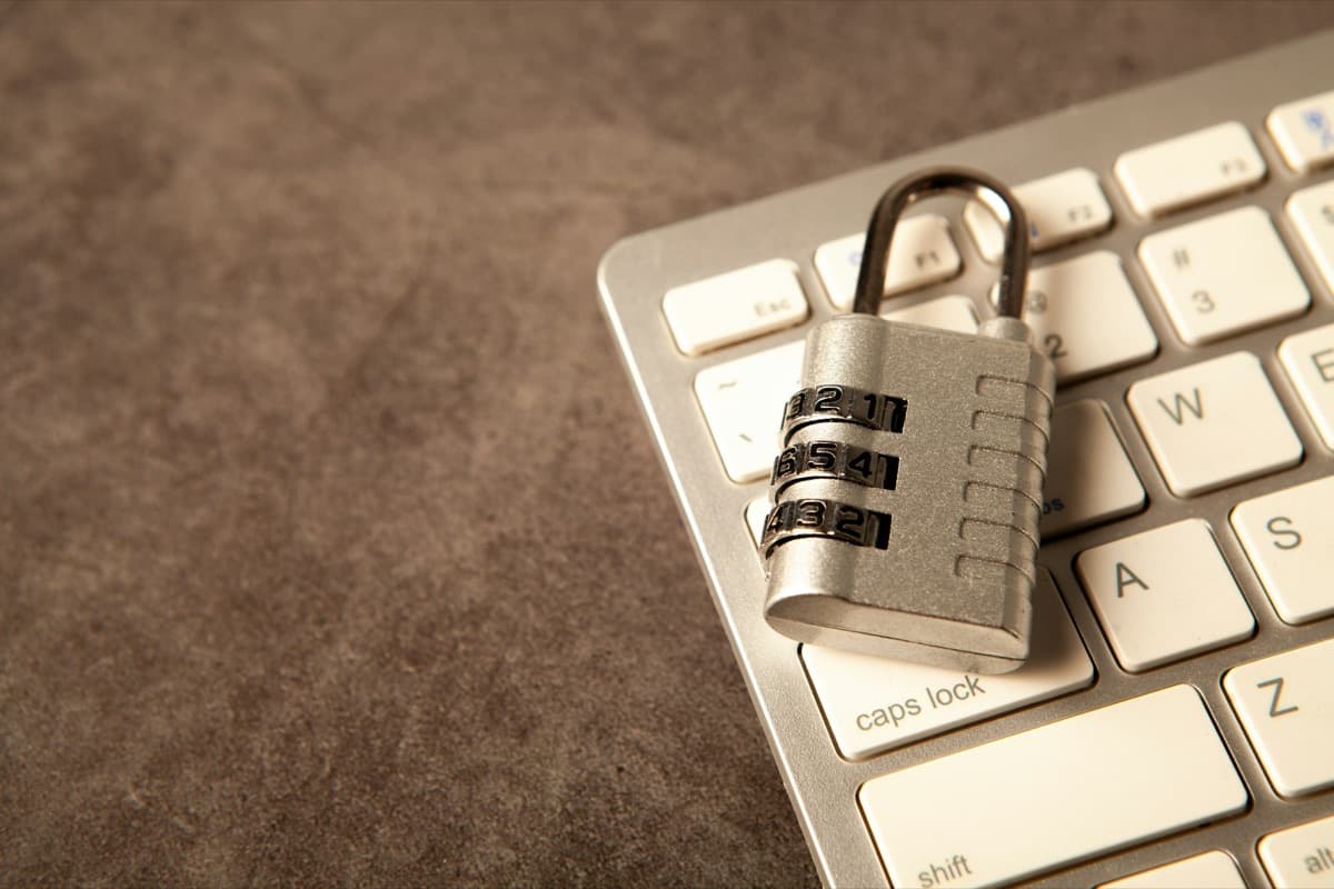 A locked combination padlock resting on a computer keyboard.